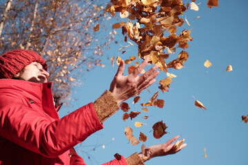 A Woman in A Red Jacket Throws Yellow Leaves. Autumn Landscape. 