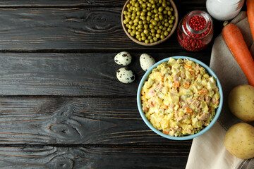 Olivier salad and ingredients on wooden background