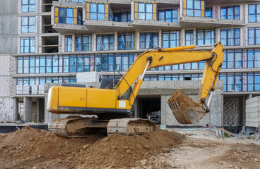 Photo of an excavator at the construction site of multi-storey buildings in the city
