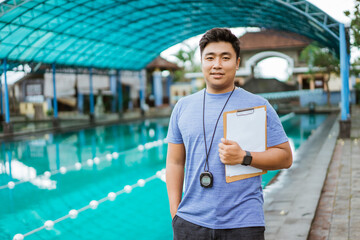 trainer holding a clipboard and wearing a stopwatch while standing