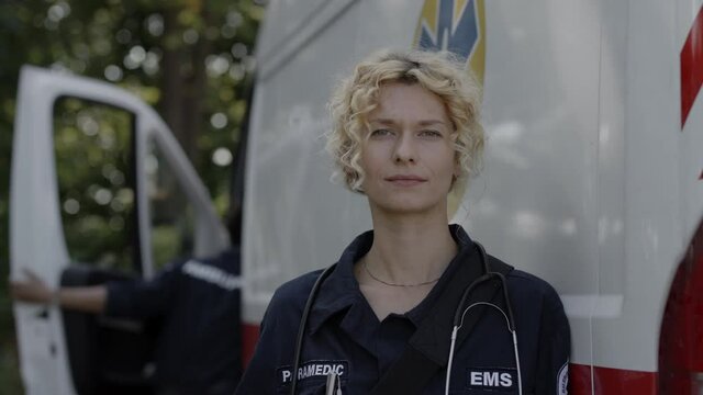Outdoors portrait of female paramedic near ambulance