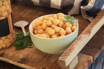 A bowl of boiled chickpeas and parsley on a rustic table