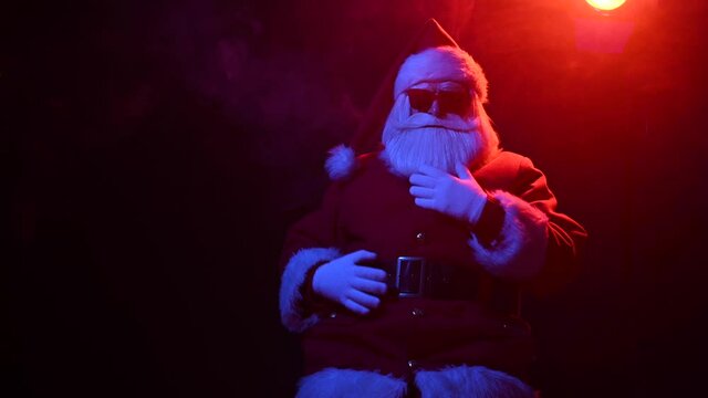 Santa claus in sunglasses among blue-red smoke. Merry Christmas.