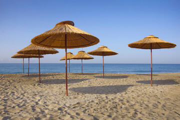 Thatched umbrellas on the beach by the sea.
