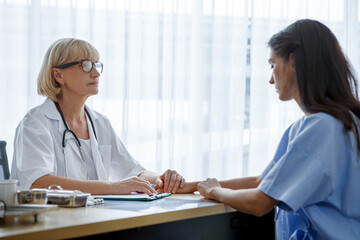 Obraz premium Senior female doctor discussing with young woman patient in clinic at hospital