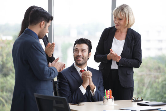 Group of business people celebrating birthday with cake to colleague in office. worker team