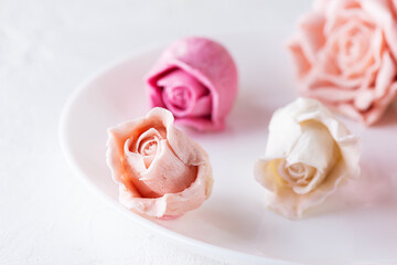Marshmallow rose buds on a white plate.