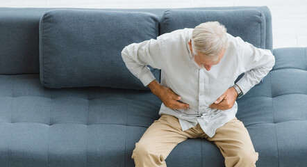 Caucasian old senior elderly stressed unhealthy gray hair and bearded man sitting on sofa in living...