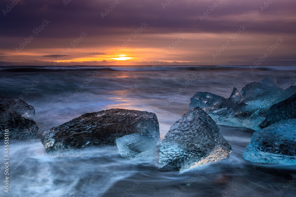 Wall mural Sunrise on Diamond Beach, Southeast Iceland. Sunlight catches large chunks of ice that have moved out from the nearby Jokulsarlon glacial lagoon.