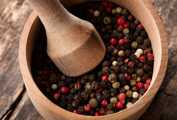 mixed coloured peppercorn in wooden bowl on wooden background