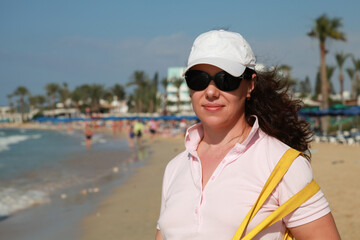 Tourist woman in sunglasses stands on a beach