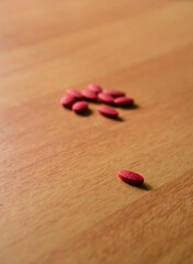Red pills on Orange background. Selective Focus, Pharmaceutical medicament. Antibiotic, painkiller or narcotic, closeup