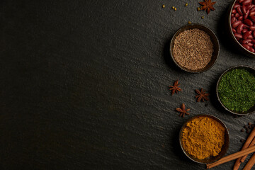 Obraz na płótnie Canvas spices concept the varieties of colors and types of spices set into small bowl on the black background with a wooden spoon