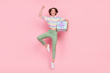 Full length photo of young girl celebrate success present box jump up isolated over pink color...