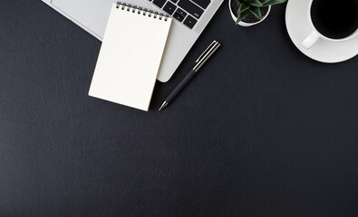 Top view above of Black leather office desk table with keyboard laptop computer, notebook with equipment other office supplies. Business and finance concept. Workplace, Flat lay with blank copy space.