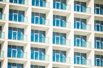 The pattern of the windows and balconies of the building. House wall with windows.