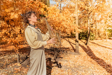 Beauty girl with saxophone in autumn park
