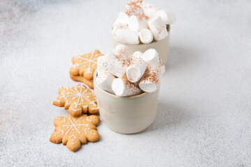 Two mugs of hot cocoa served with marshmallow on a gray background, copy space