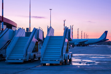 Empty passenger boarding steps near the aircraft on the airport apron against the backdrop of a...