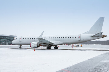 Fototapeta na wymiar White passenger aircraft on the airport apron in a blizzard