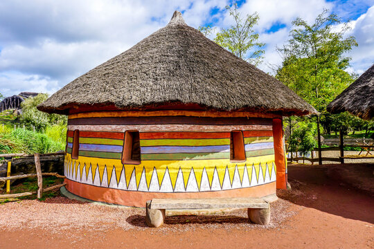 Traditional African house with colorful painted walls and a bench in front of the house
