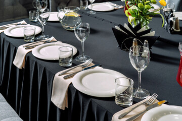 Table setting for a wedding or dinner event, black tablecloth white plates.