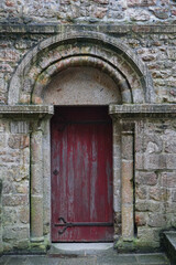 Fototapeta na wymiar Red painted antique door at the entrance of a castle with a beautiful dome carved in stone