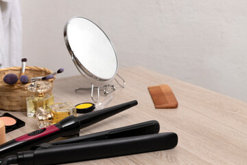 Set of hair dressing tools,cosmetcs,make up accessories and mirror on the wooden table against bath wall.Empty space