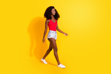 Fototapeta na wymiar Full length body size profile side view of attractive cheerful thin girl walking wearing season clothes isolated over bright yellow color background