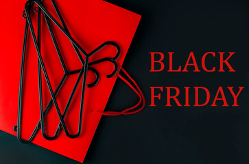 Black hanger and red bag on black background. Black friday text