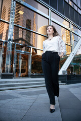 Young business woman on the street with glass mirror building behind