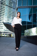 Young business woman in front of glass mirror building in the city in white black suit