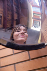 Reflection in the mirror of white european woman outside in an industrial area