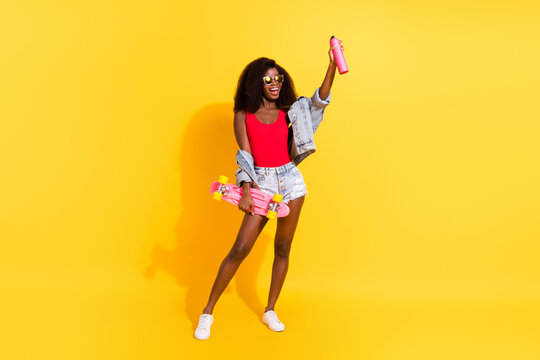 Full length body size photo of girl keeping spray for graffiti skate board wearing sunglass isolated on vivid yellow color background
