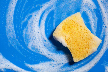 cleaning sponge wiping foam soap suds on blue background, household washing concept - obrazy, fototapety, plakaty