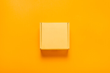 Simple yellow cardboard box on color background, top view
