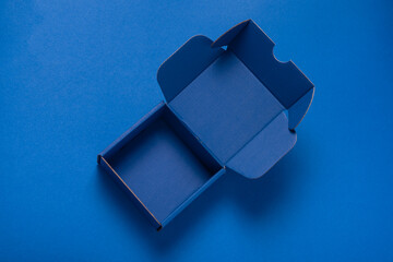 Simple blue cardboard box on color background, opened, empty inside