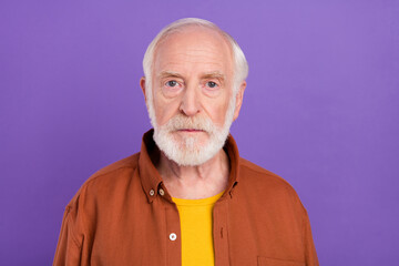 Photo of serious elder man wearing brown shirt isolated over vivid violet color background