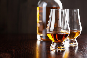Bottle and glass of whisky spirit brandy on dark brown background