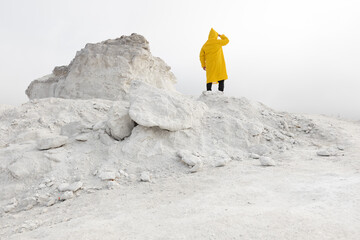 Man lost on a white stalker mountain in fog wearing yellow raincoat
