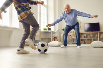 Grandpa and grandson playing soccer at home. Child and grandfather spending time together. Little...