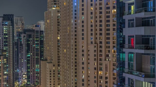 Overview to JBR and Dubai Marina skyline with modern high rise skyscrapers waterfront living apartments aerial night timelapse