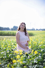 Smiling white young woman with long hair in light dress in the countryside in the field of flowers
