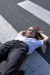 Dark blond slim young woman lying on pedestrian crossing