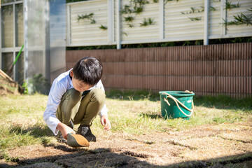 庭に芝生を植えるお手伝いをする小学生