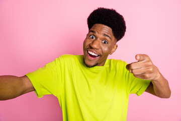 Self-portrait of attractive trendy cheerful guy pointing at you having fun isolated over pink...