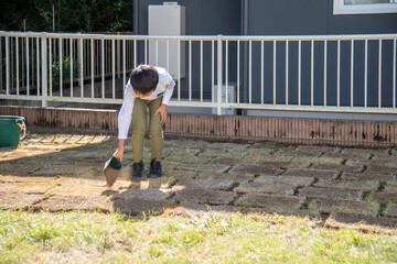 庭に芝生を植えるお手伝いをする小学生