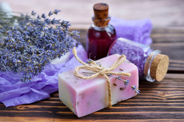 Lavender spa products on wooden table. Body care products with lavender: soap, oil, salt and dried lavender flowers. Selective focus.