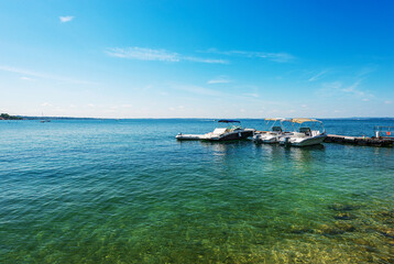 Group of small speedboats moored on the coast of Lake Garda (Lago di Garda) in front of the...