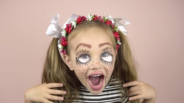A little girl with make-up on her face depicts puppet grimaces. Carnival costume.Close-up